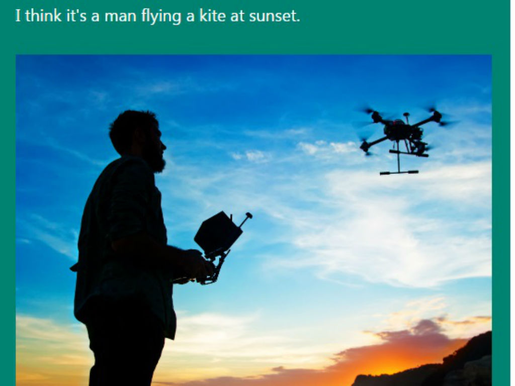 En esta Captionbot cree que es un hombre volando una cometa en el atardecer. Casi. 