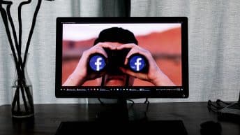 Pantala de un computador que muestra a una persona mirando por unos binoculares con el logo de Facebook